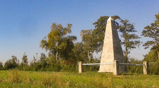 Auf einem Feld steht ein Obelisk mit pyramidenförmiger Spitze, die Basispyramide von Aufkirchen.
